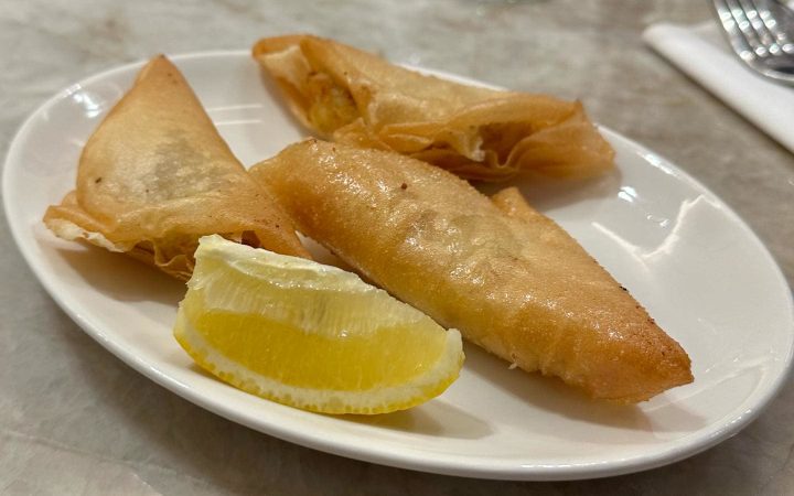 Trois briks dorées servies sur une assiette blanche avec une tranche de citron