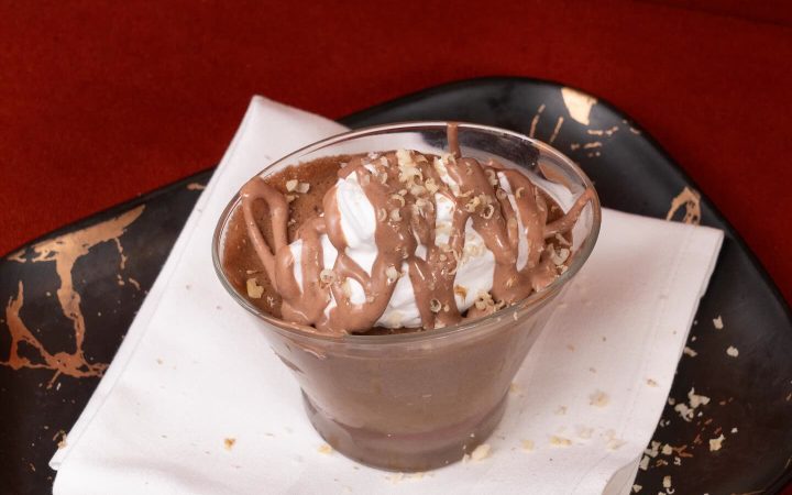 Un dessert au chocolat et à la crème servi dans un verre sur une serviette blanche