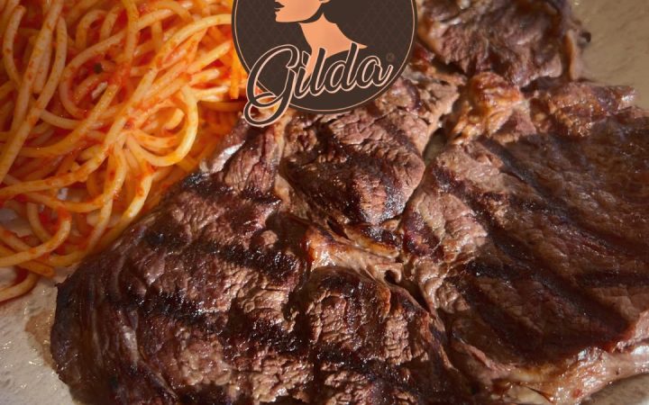 Un steak grillé accompagné de spaghettis à la sauce tomate dans une assiette