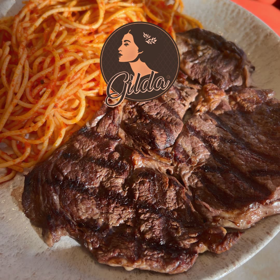 Un steak grillé accompagné de spaghettis à la sauce tomate dans une assiette