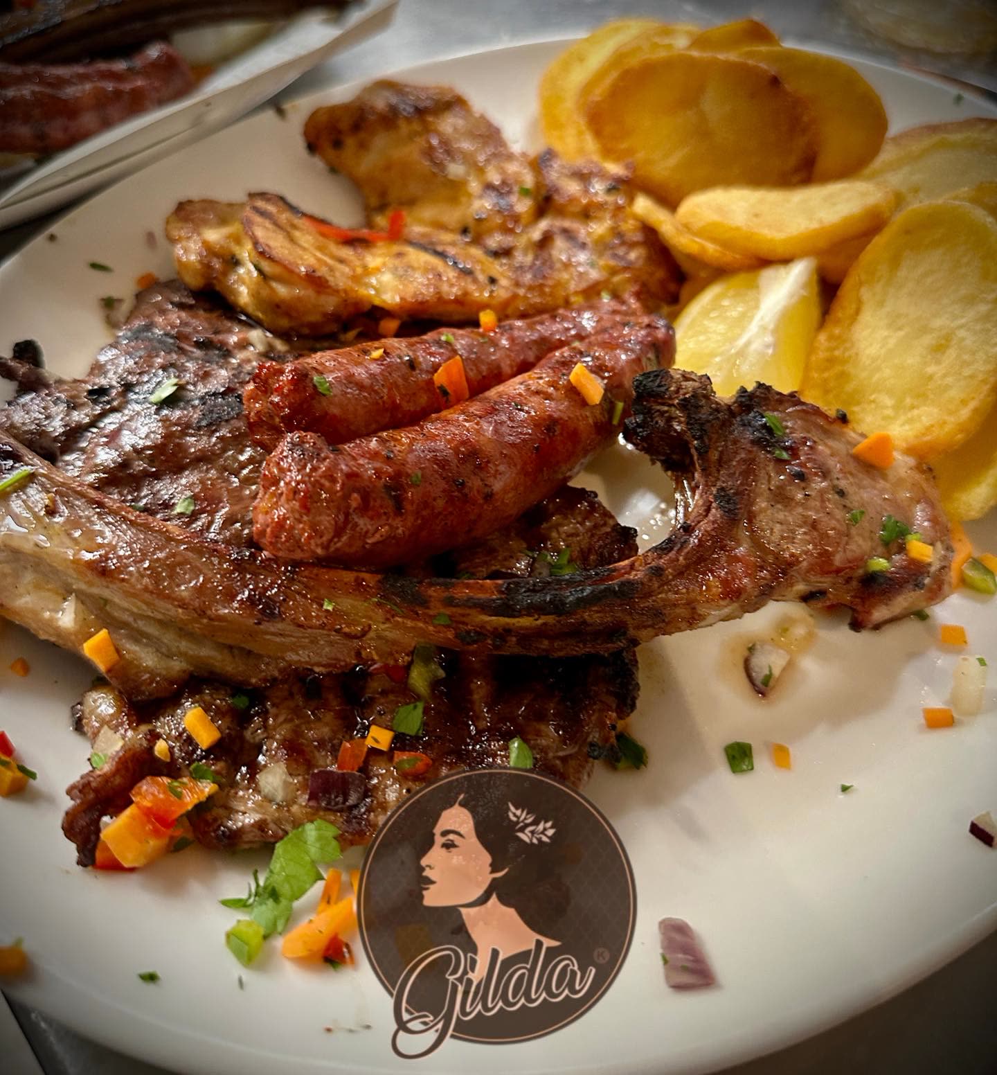 Assiette de grillades comprenant des merguez, des côtes d'agneau et du poulet avec des pommes de terre