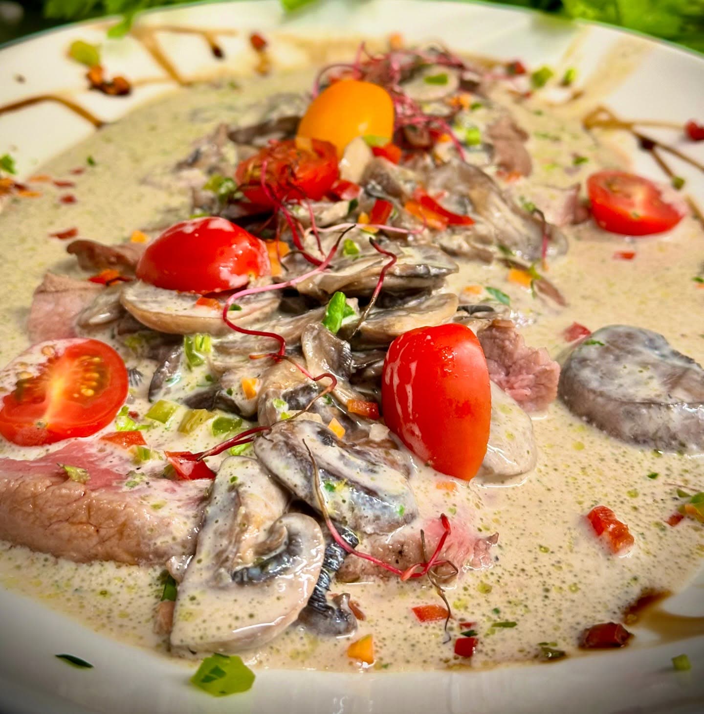 Tranches de viande servies dans une sauce crémeuse avec des champignons et des tomates cerises