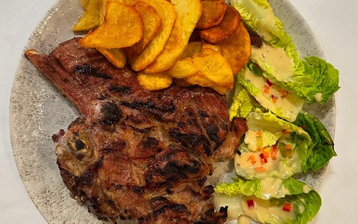 Une côtelette de viande grillée accompagnée de pommes de terre et d'une salade verte