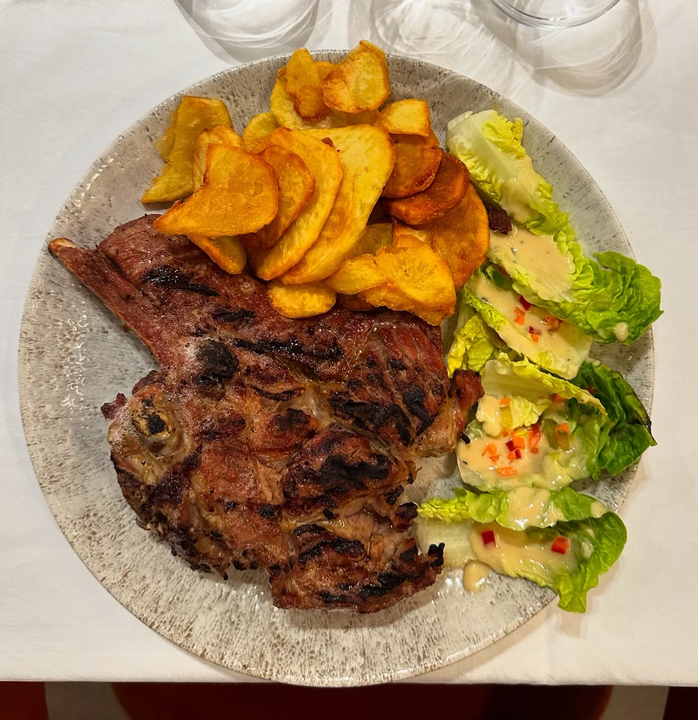 Une côtelette de viande grillée accompagnée de pommes de terre et d'une salade verte