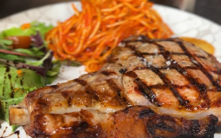 Une côtelette de viande grillée servie avec des carottes râpées et une salade verte