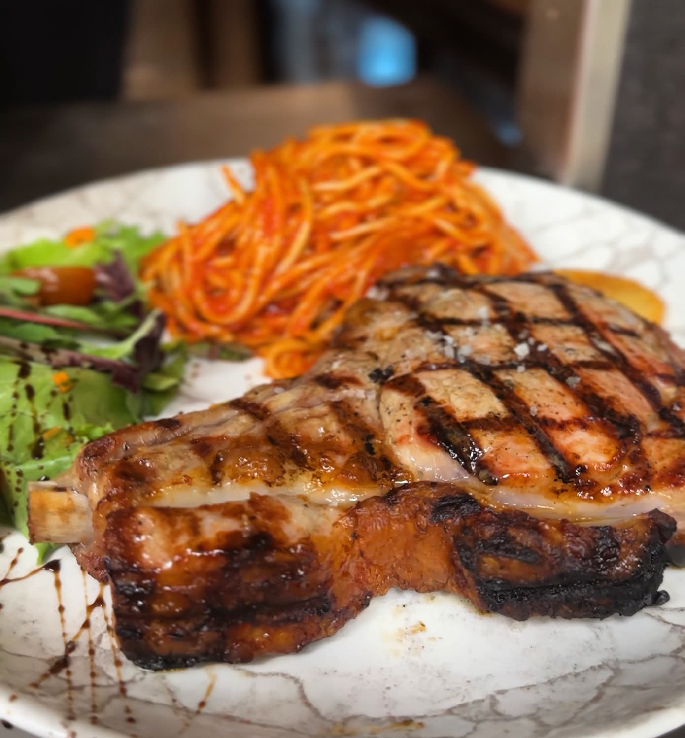 Une côtelette de viande grillée servie avec des carottes râpées et une salade verte