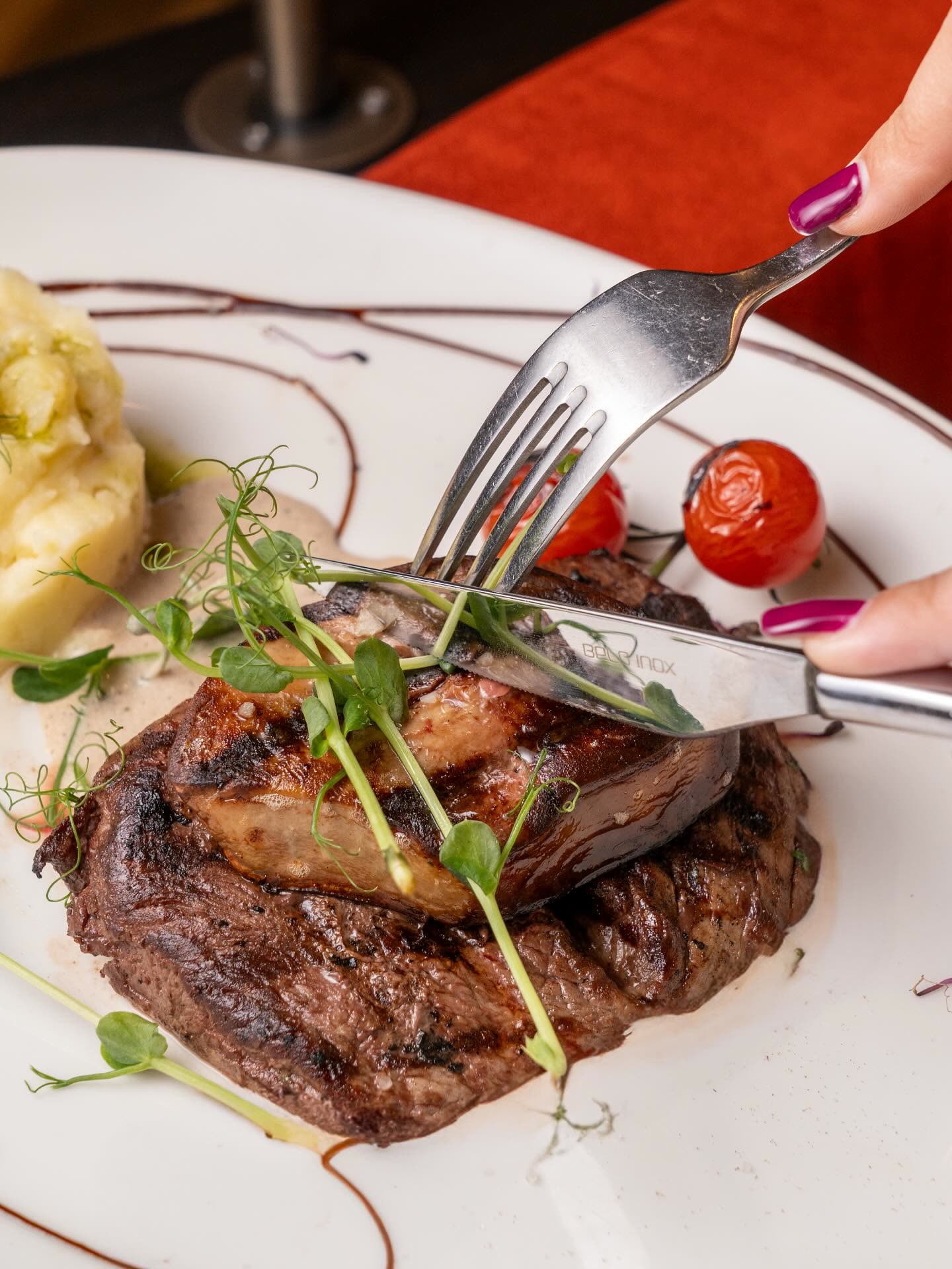 Un morceau de viande grillée avec des tomates cerises et des pousses de pois sur une assiette blanche