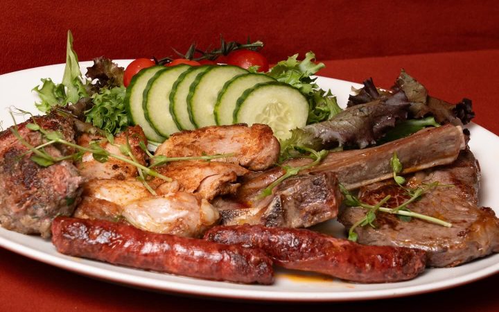 Une assiette de grillades de viande accompagnée de tranches de concombre et de salade