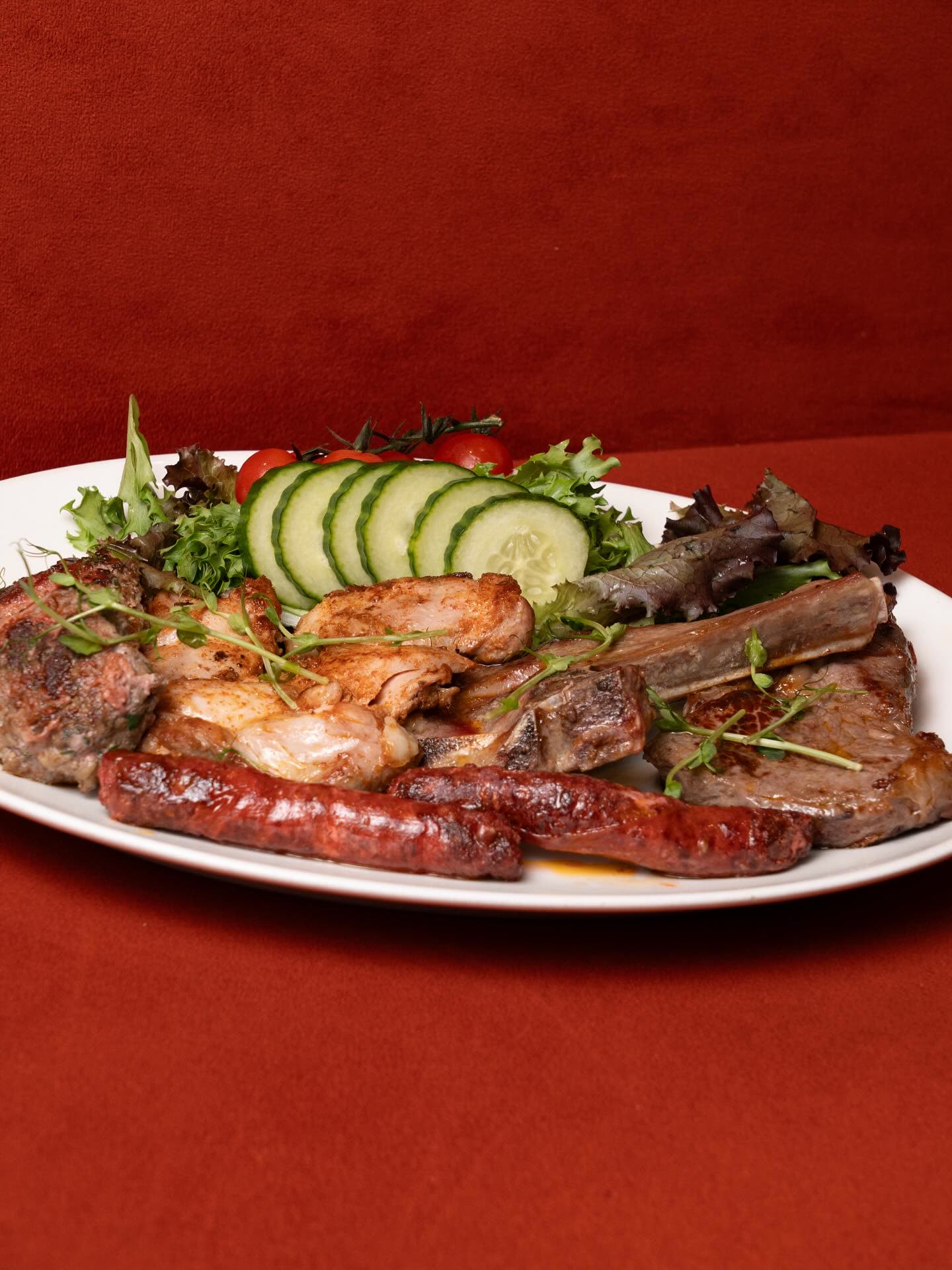 Une assiette de grillades de viande accompagnée de tranches de concombre et de salade