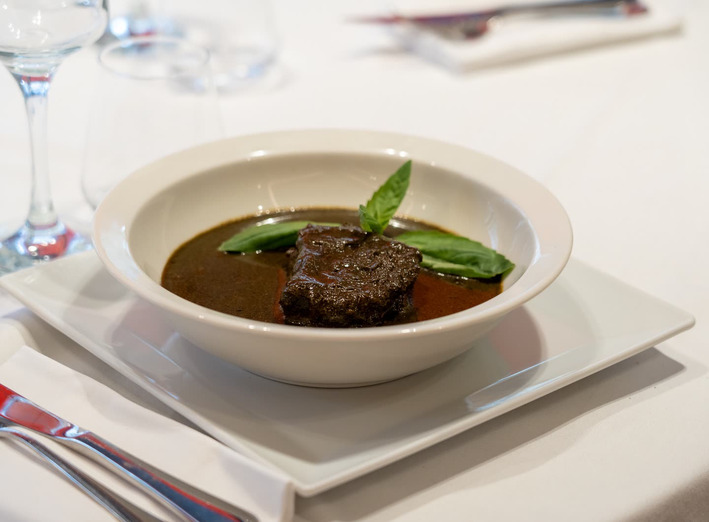 Un morceau de viande dans une sauce brune servie dans un bol blanc