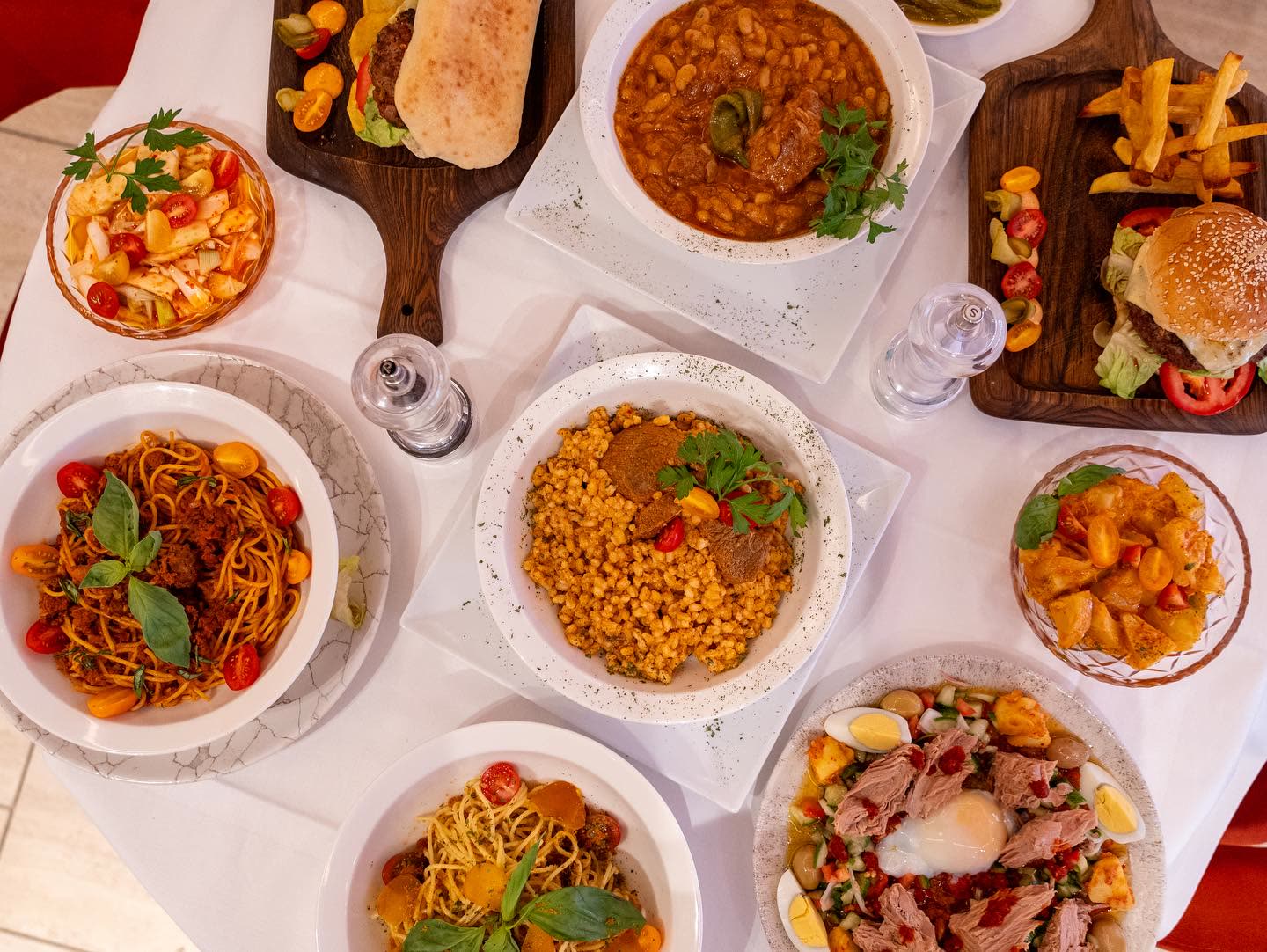 Une vue de dessus montrant plusieurs plats de cuisine tunisienne et méditerranéenne sur une table blanche