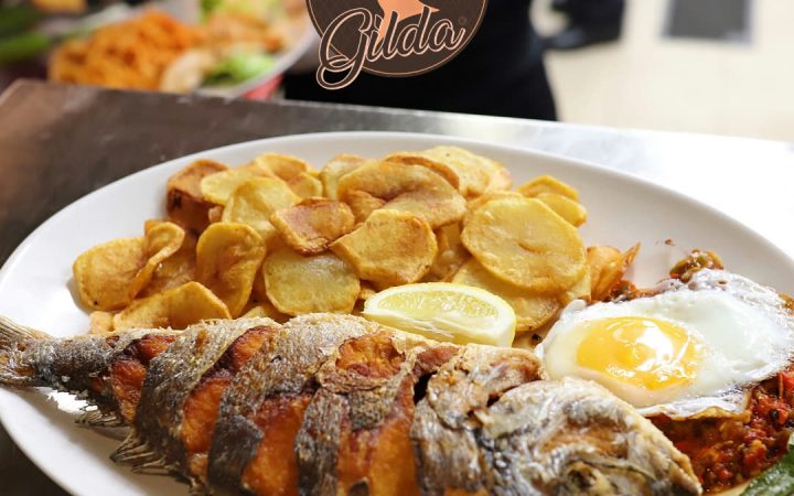 Un poisson entier frit servi avec des rondelles de pommes de terre et un œuf au plat