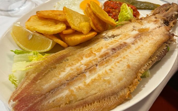 Un poisson entier frit servi avec des pommes de terre et une salade