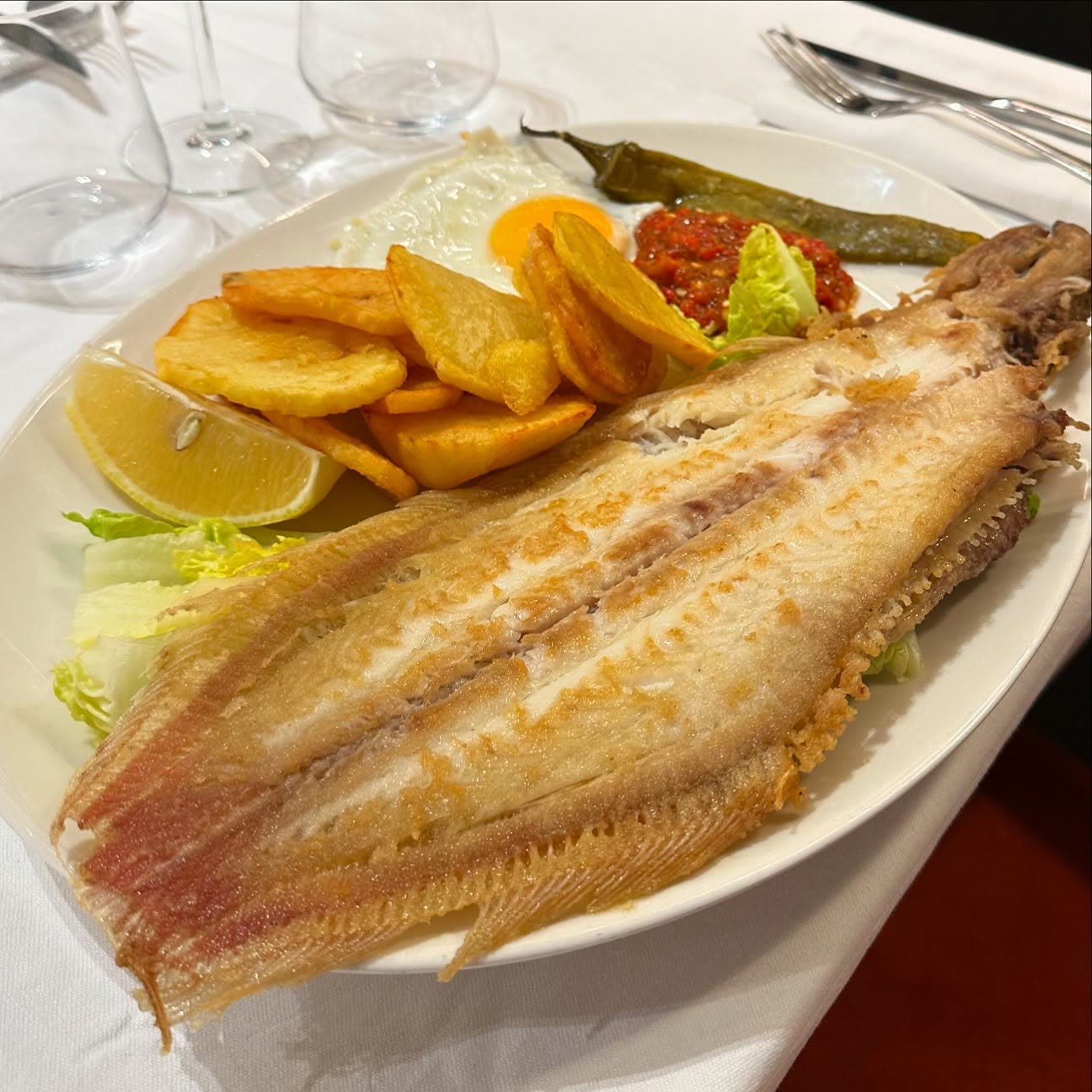 Un poisson entier frit servi avec des pommes de terre et une salade