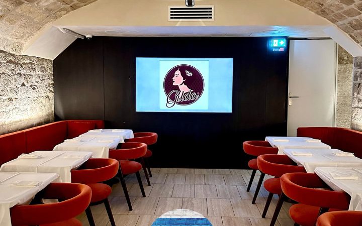 L'intérieur d'un restaurant avec des tables blanches, des chaises rouges et un plafond voûté en pierre
