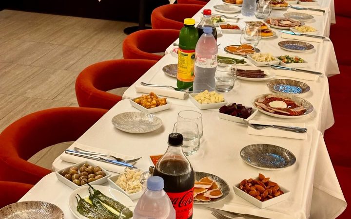 Une table longue dressée avec de nombreux petits plats, des boissons et des couverts pour un repas de groupe