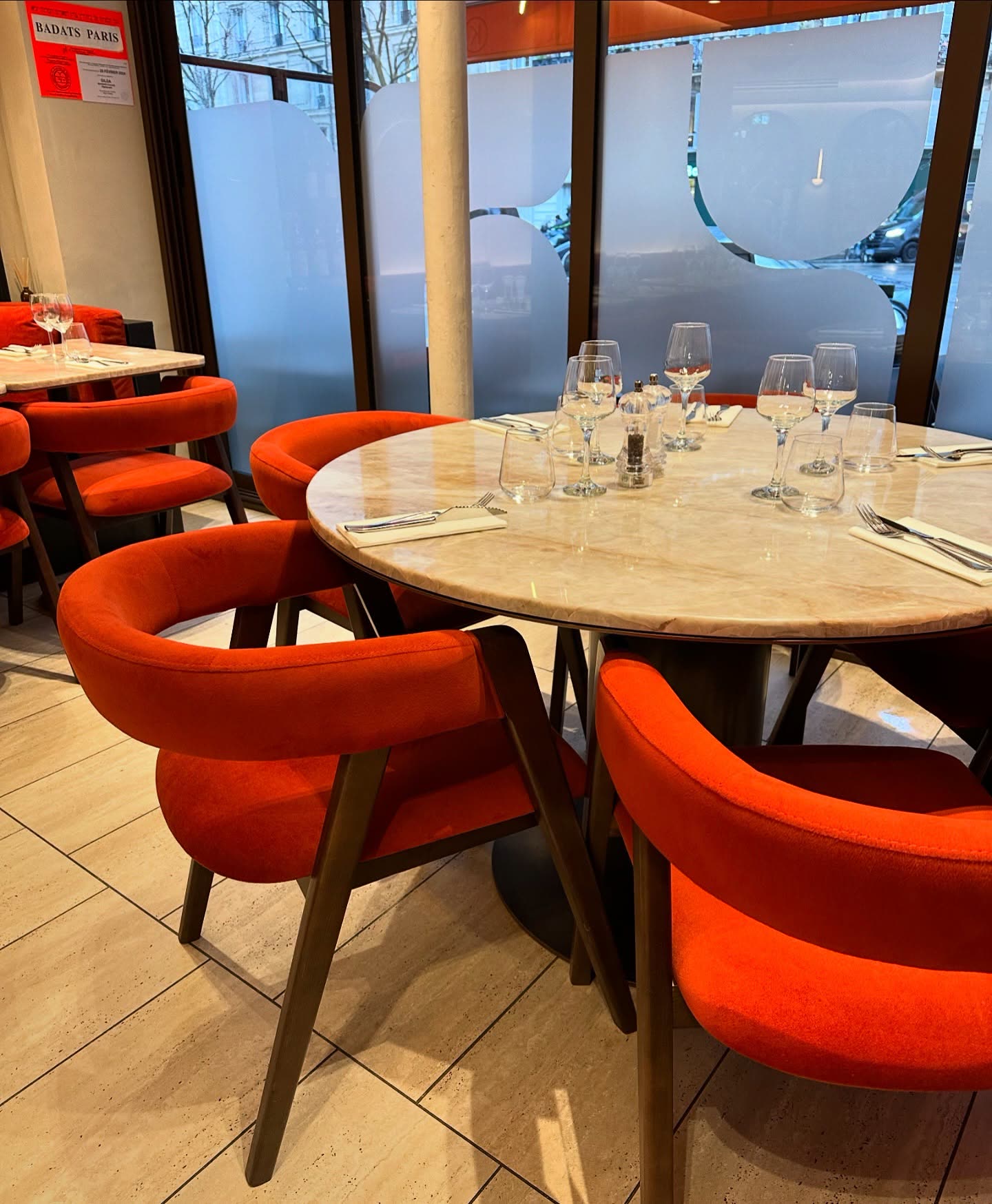 Une table ronde en marbre dressée avec des verres dans un restaurant