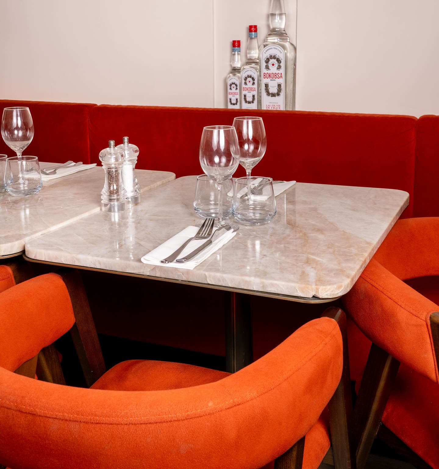 Une table en marbre dressée avec des verres, des couverts et des bouteilles en arrière-plan