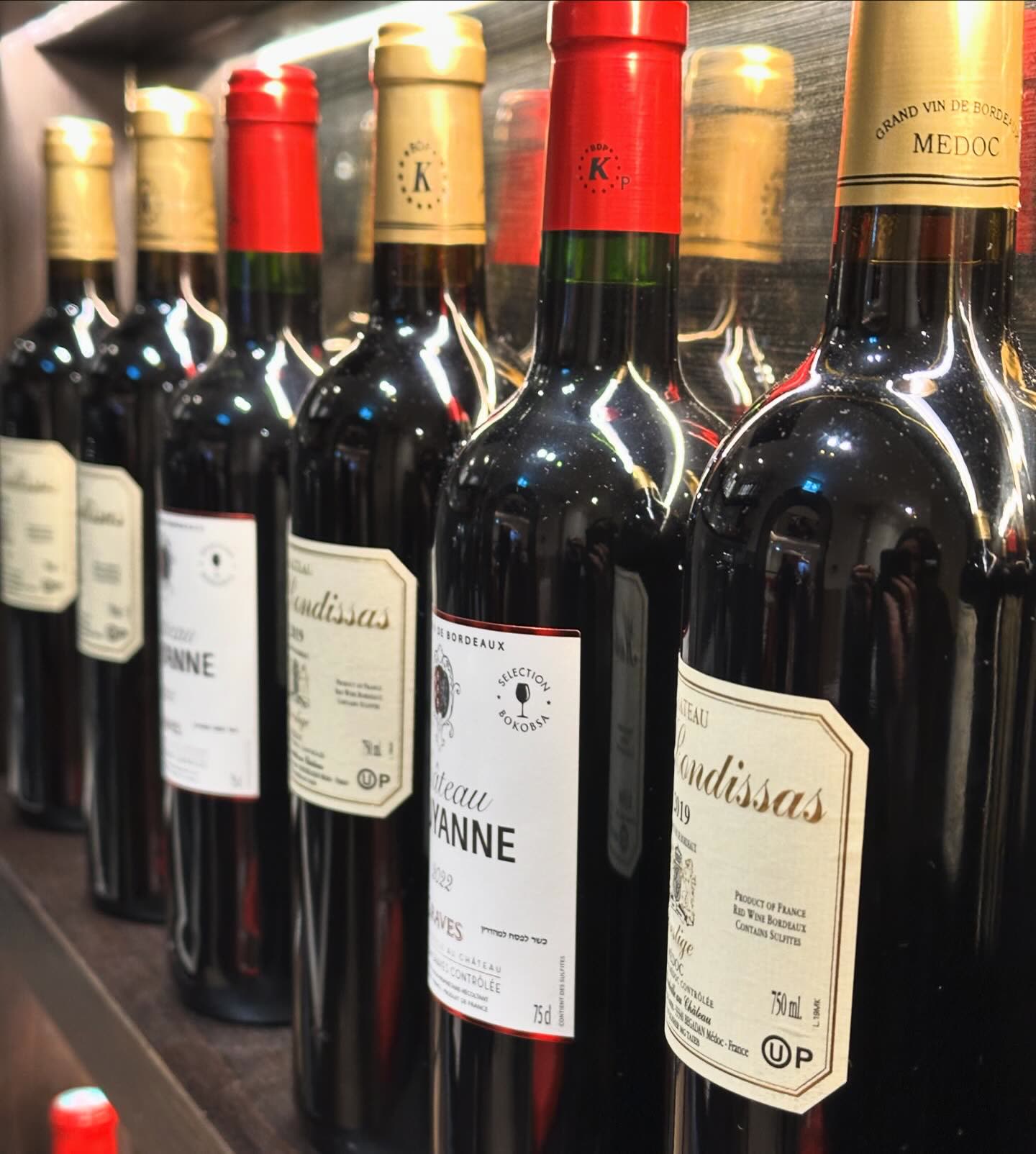 Plusieurs bouteilles de vin rouge alignées sur une étagère